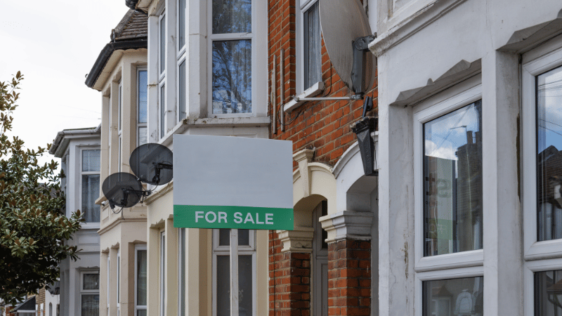 Residential terraced houses with a Green For Sale sign representing the best UK property investment opportunities and buy-to-let locations for 2026